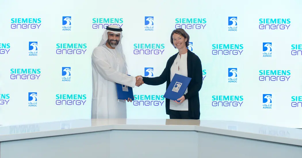 image is Sophie Hildebrand, ADNOC CTO And Dr. Fahad Al Yafei, Siemens Energy Middle East CTO Exchange Copies Of The Agreement At ADIPEC 2022